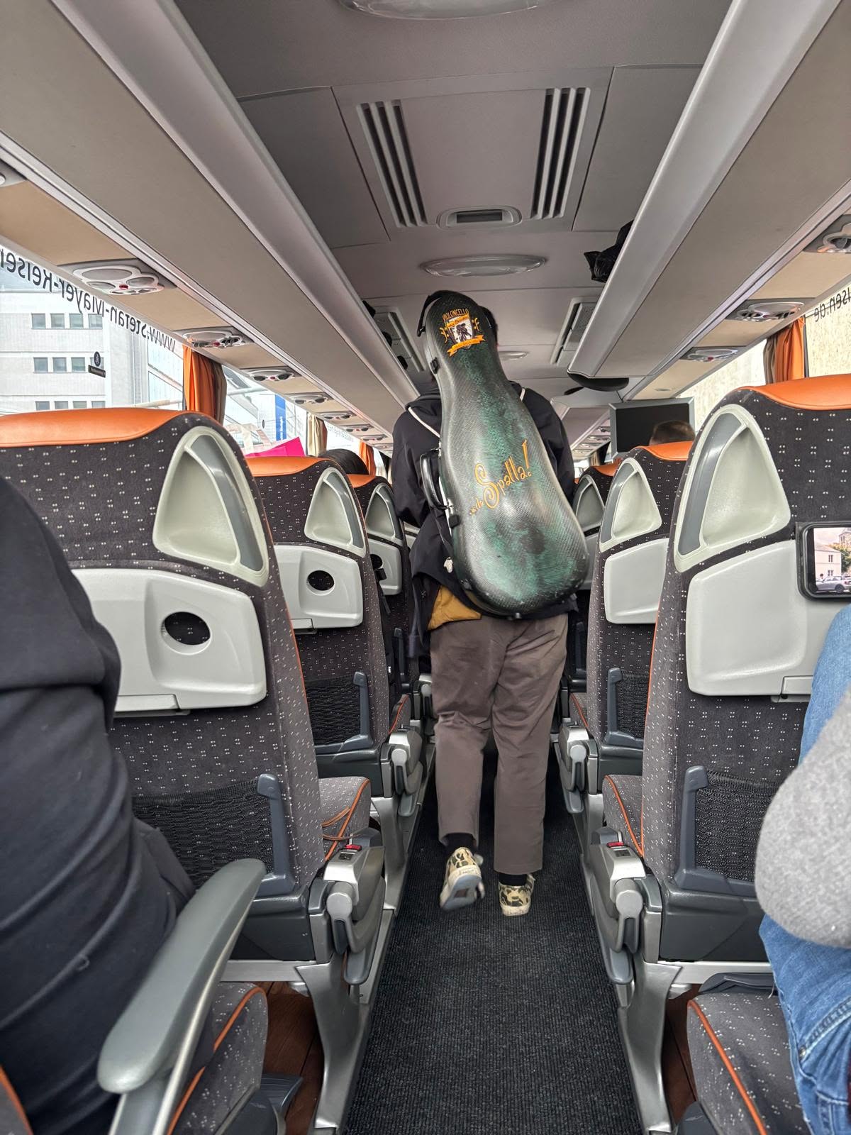 Musician with cello case boarding a tour coach